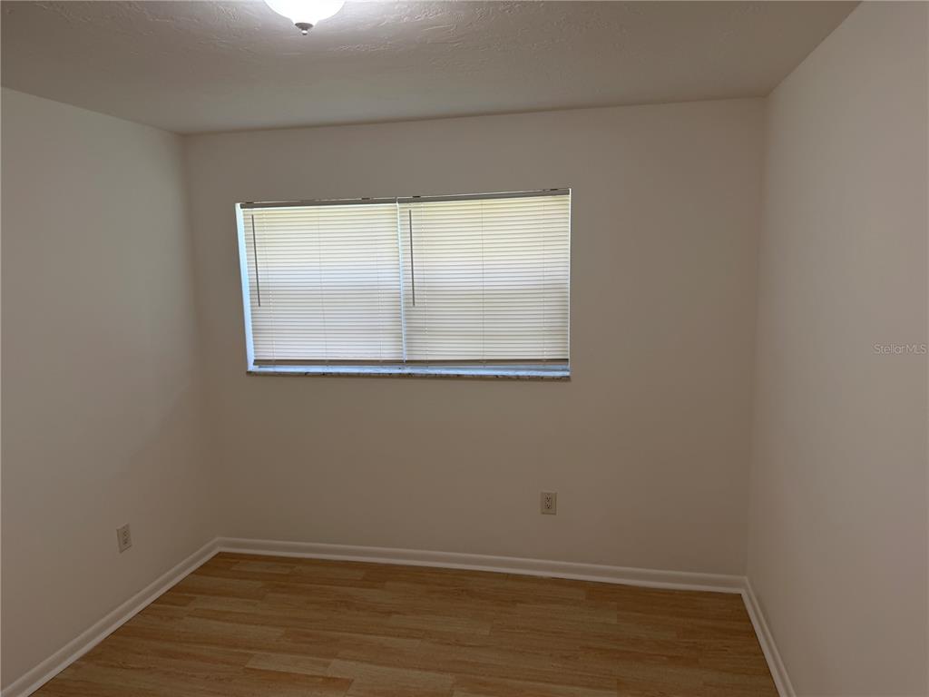 An empty bedroom features light wood-look flooring, white walls, and a window with blinds — 2185 NW 3RD STREET, OKEECHOBEE, FL