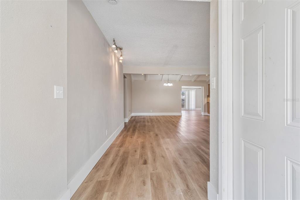 A view through a doorway into a living area with light wood-look flooring — 13691 SERENA DRIVE, LARGO, FL