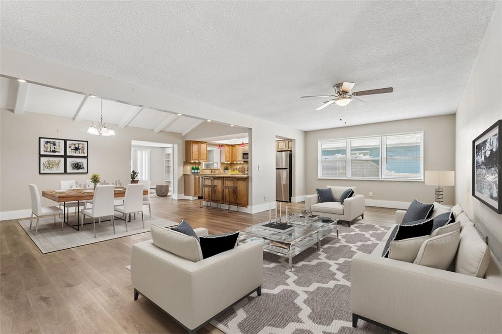 An open-concept living and dining area features light wood flooring, neutral walls, and modern furniture — 13691 SERENA DRIVE, LARGO, FL