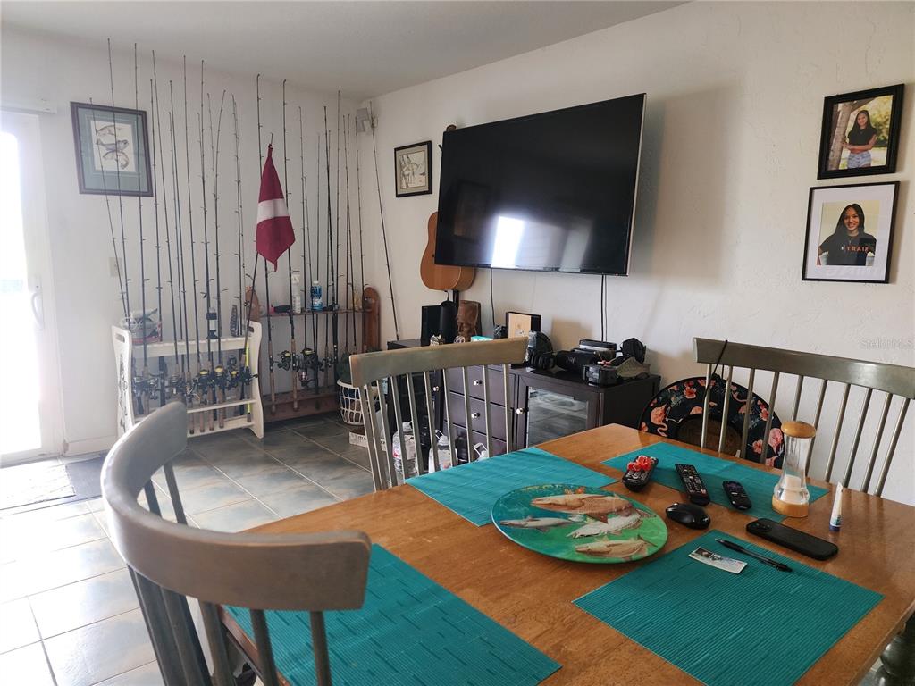 A dining room features a wooden table, fishing rod storage, and a wall-mounted television — 200 MERES BOULEVARD UNIT 19, TARPON SPRINGS, FL