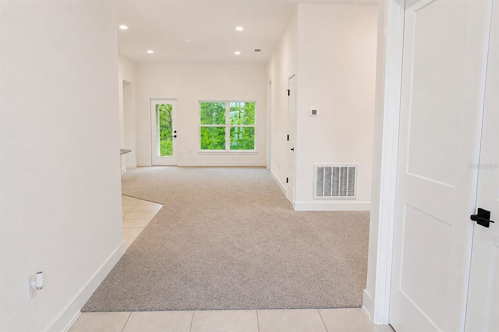 An interior view shows a carpeted living area with a glass door and large windows — 7592 BENT TREE LOOP, ST CLOUD, FL