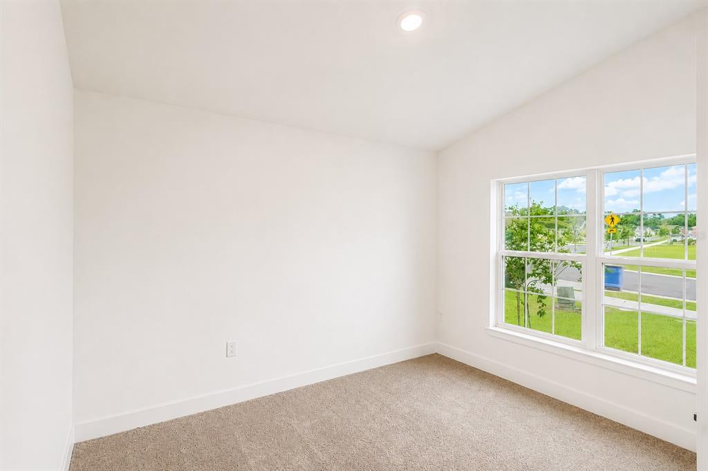 An empty bedroom features beige carpet, white walls, a recessed ceiling light, and a window — 7592 BENT TREE LOOP, ST CLOUD, FL