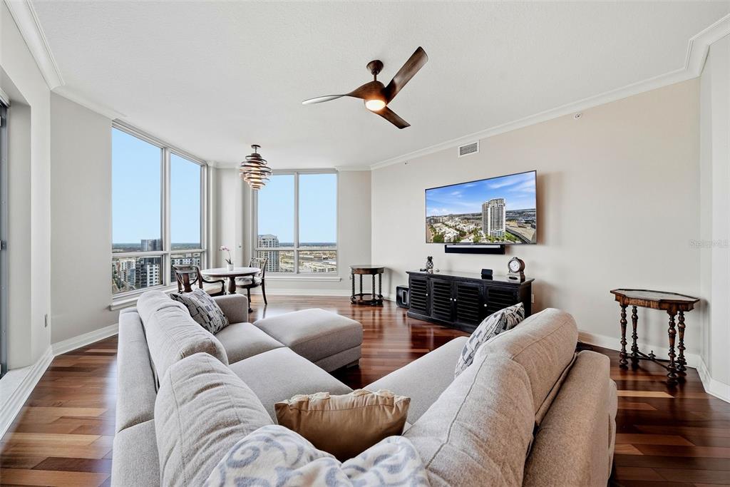 A living room with hardwood floors, a sectional sofa, a wall-mounted television, and floor-to-ceiling windows — 449 SOUTH  12TH UNIT 2301, TAMPA, FL
