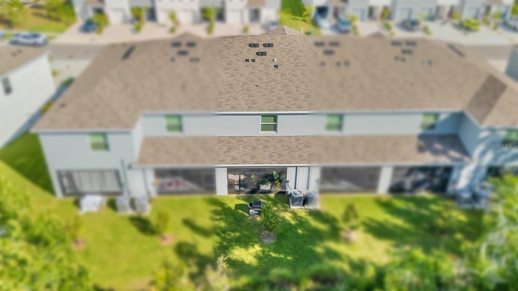 An aerial view shows the back of a multi-unit townhouse with screened-in lanais — 5052 CAPTAIN DAVIS DRIVE, WIMAUMA, FL