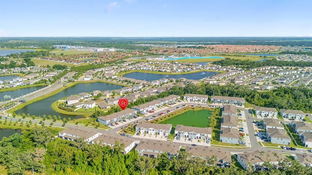 This aerial view shows a residential neighborhood with townhomes, ponds, and surrounding green space — 5052 CAPTAIN DAVIS DRIVE, WIMAUMA, FL
