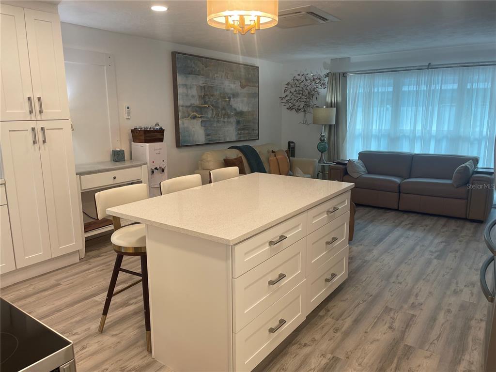 A kitchen island with white cabinets and quartz countertops sits in an open-concept living space — 515 1ST AVENUE E, BRADENTON, FL