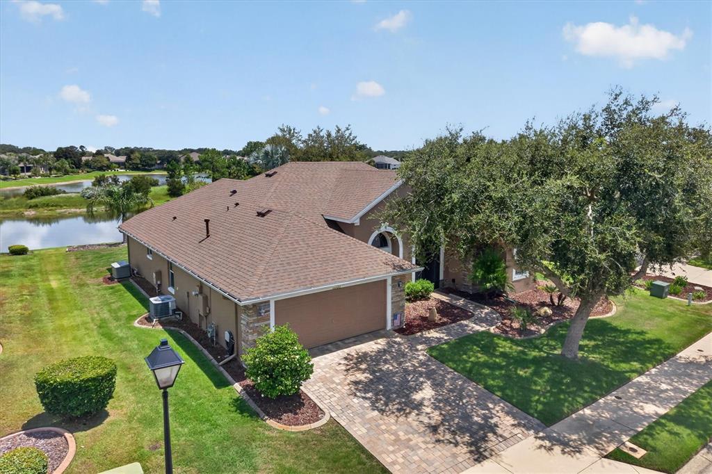 An aerial view shows a single-story house with a brown roof, stone accents, and a driveway — 8920 BRIDGEPORT BAY CIRCLE, MOUNT DORA, FL