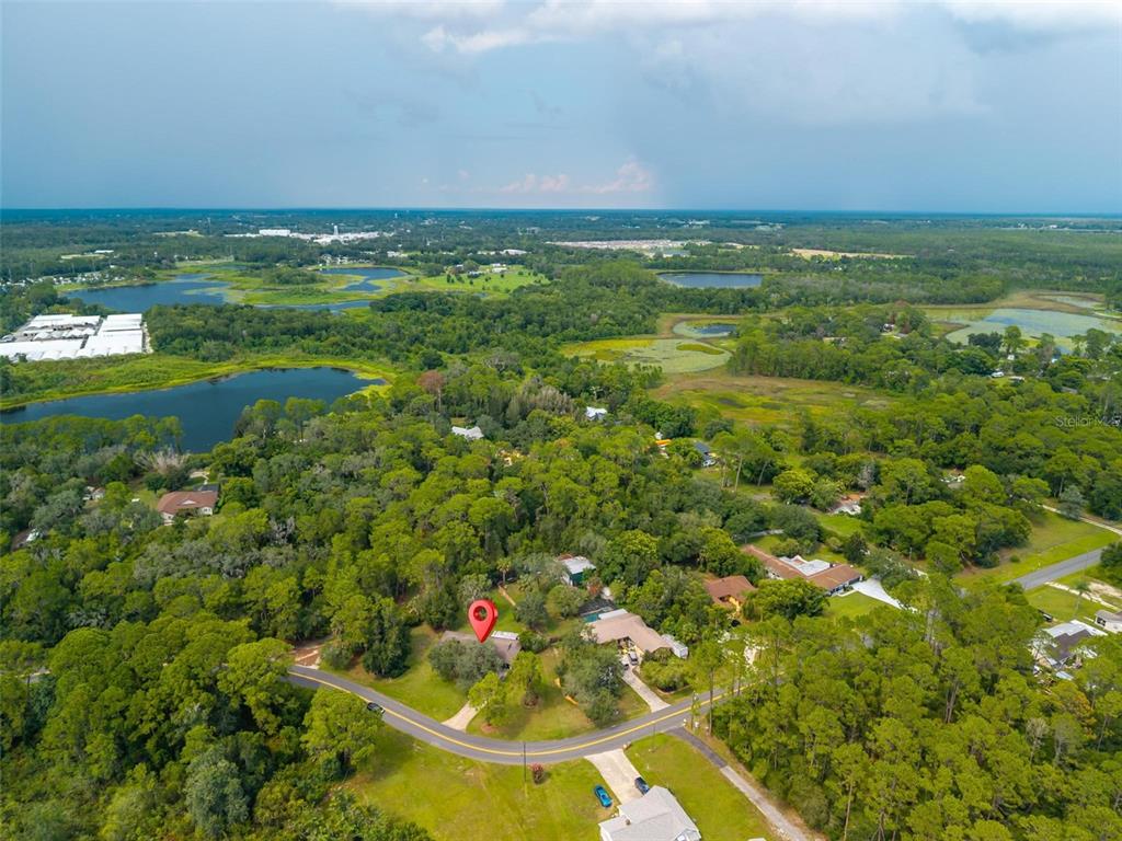 An aerial view shows a house with a red location pin amidst a wooded landscape — 16529 ORANGE AVENUE, UMATILLA, FL