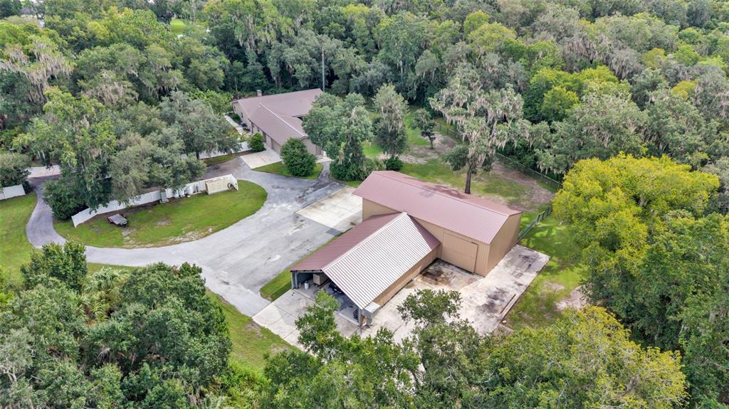 An aerial view shows a house and a large detached garage surrounded by dense trees — 6400 FORESTWOOD DRIVE E, LAKELAND, FL