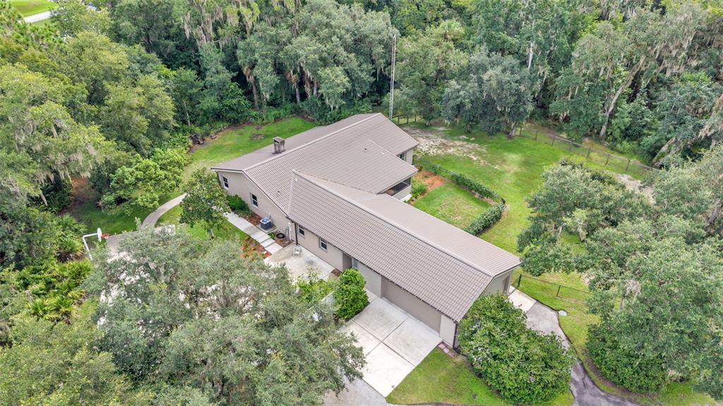 A single-story house with beige siding, a covered porch, and a dark metal roof — 6400 FORESTWOOD DRIVE E, LAKELAND, FL