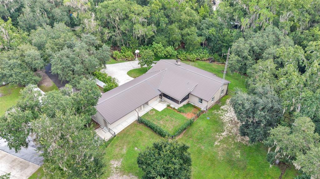 A single-story house with beige siding, a metal roof, and a concrete walkway — 6400 FORESTWOOD DRIVE E, LAKELAND, FL