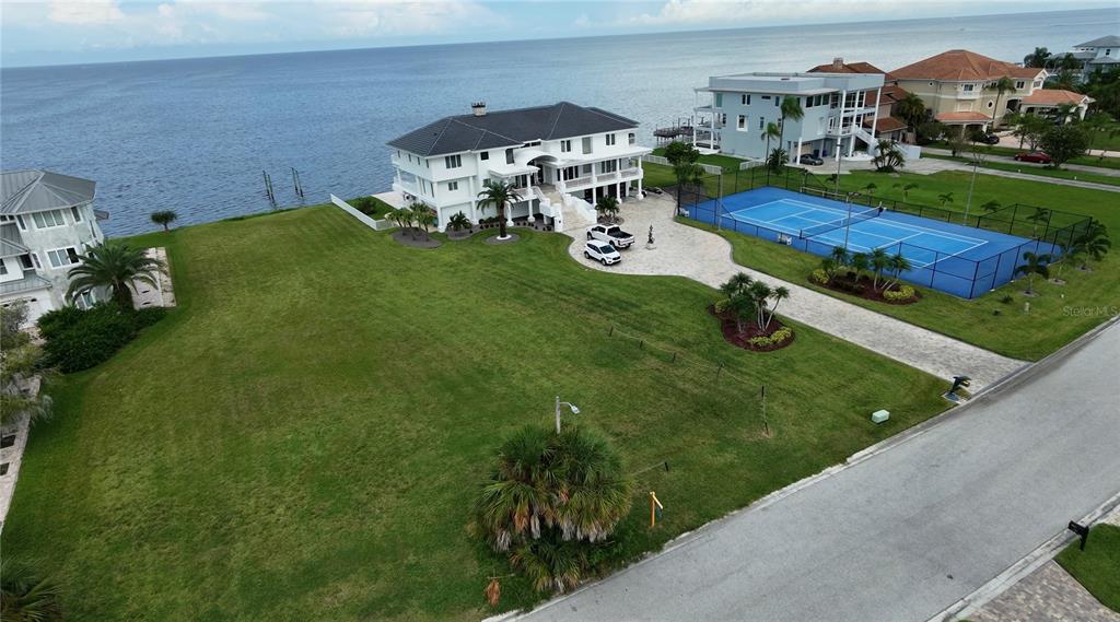 An aerial view shows a sandy beach with palm trees, picnic shelters, and a parking lot — 21 WESTSHORE DRIVE, NEW PORT RICHEY, FL