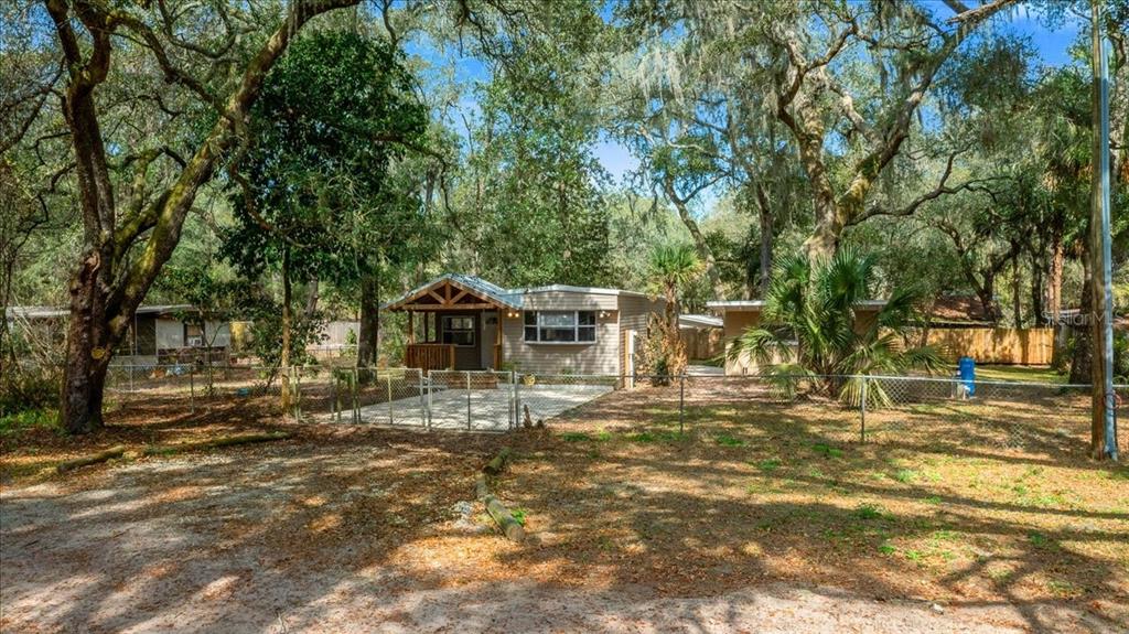 A single-story house with a front porch sits on a wooded lot behind a fence — 16789 SE 8TH PLACE, SILVER SPRINGS, FL