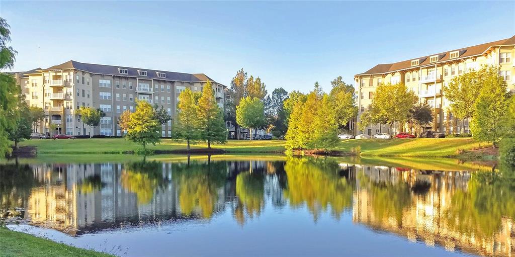 A pond reflects two large apartment buildings surrounded by green lawns and trees — 1400 CELEBRATION AVE UNIT 102, CELEBRATION, FL