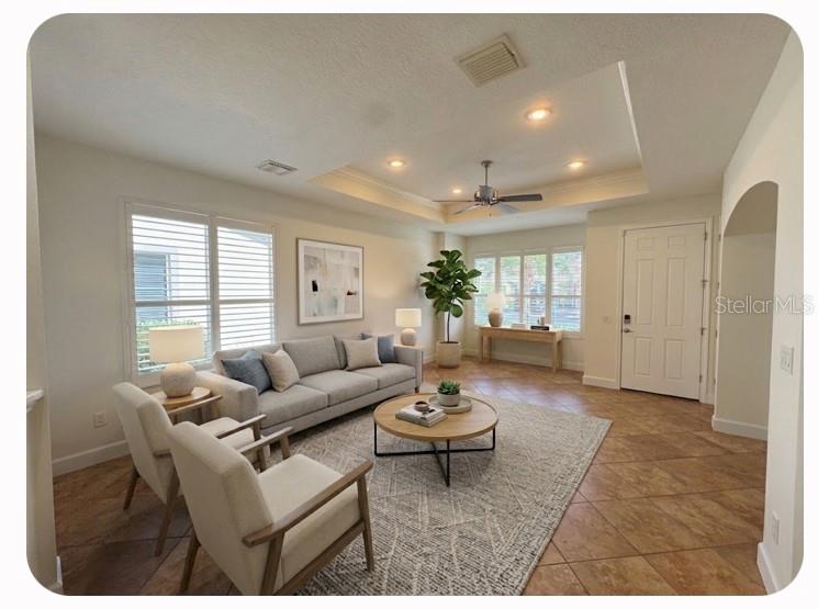 A living room features a tray ceiling, tile flooring, a sofa, two armchairs, and windows — 1140 BEACHCOMBER COURT UNIT 11, OSPREY, FL