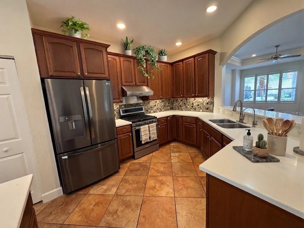 A kitchen features wood cabinets, stainless steel appliances, white countertops, and brown tile flooring — 1140 BEACHCOMBER COURT UNIT 11, OSPREY, FL