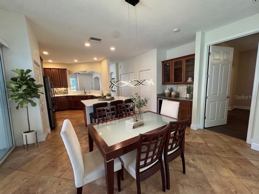 A dining area with a glass-topped table and chairs sits adjacent to a kitchen island — 1140 BEACHCOMBER COURT UNIT 11, OSPREY, FL