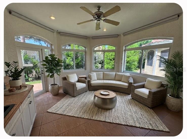 A sunroom features wicker furniture, a curved sofa, tile flooring, and large arched windows — 1140 BEACHCOMBER COURT UNIT 11, OSPREY, FL