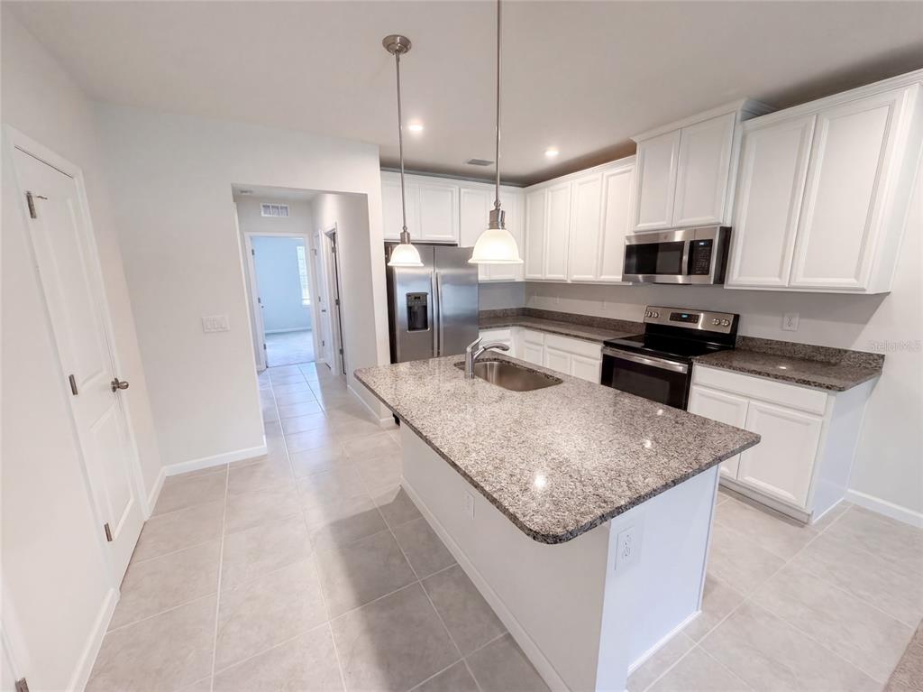 A kitchen with white cabinets, granite countertops, a center island, and stainless steel appliances — 17917 TURNING LEAF CIRCLE, LAND O LAKES, FL
