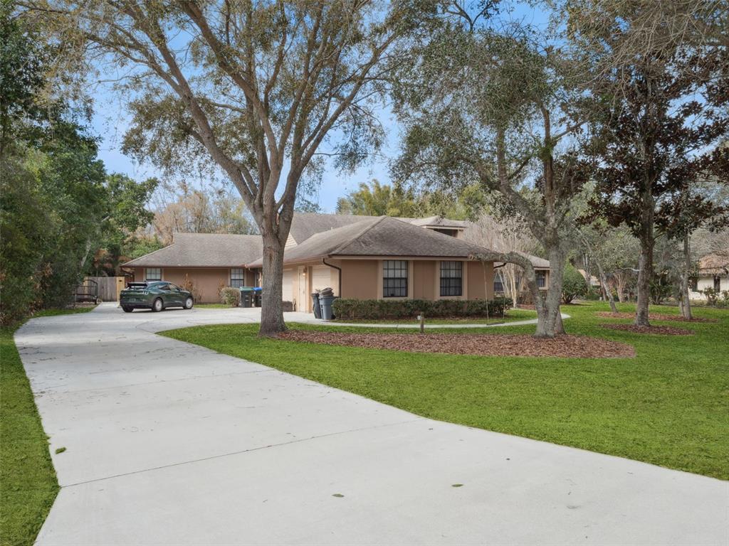 A single-story house with a concrete driveway, a green car, and mature trees — 5314 SHADYWOOD LANE, ORLANDO, FL