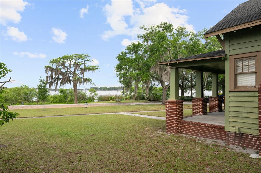 A view from a porch looking across a lawn toward a lake with large trees — 230 KILLARNEY DRIVE, WINTER PARK, FL