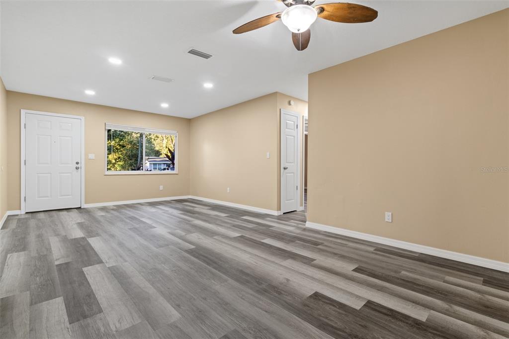 A living room features light-colored walls, gray wood-look flooring, a ceiling fan, and a window — 609 HOLLEY STREET, BROOKSVILLE, FL