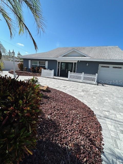 A gray house with a white picket fence and a paved driveway under a blue sky — 9312 KINGSTON ROAD, BRADENTON, FL