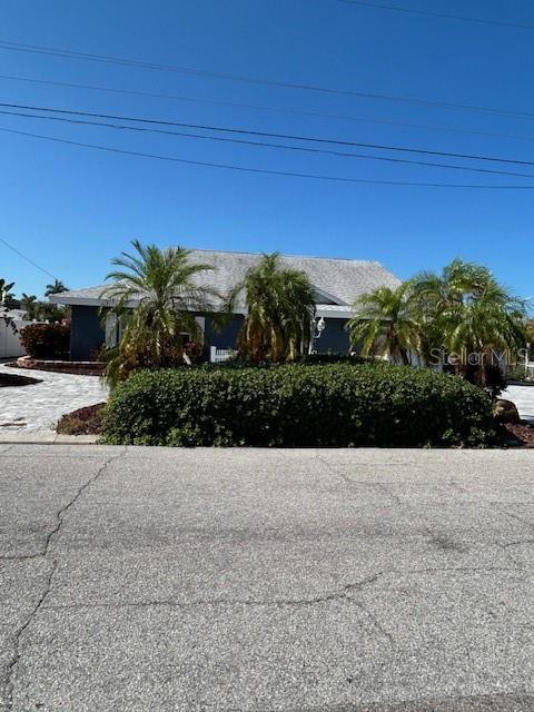 A single-story house with a gray roof and palm trees sits behind a large hedge — 9312 KINGSTON ROAD, BRADENTON, FL