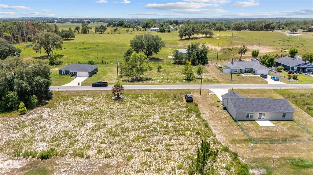An aerial view shows a vacant lot next to a house with a paved road — 0 MALAUKA LOOP, OCKLAWAHA, FL