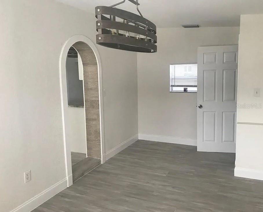 A dining room features gray wood-look flooring, an arched doorway, and a rustic chandelier — 1200 EMERALDA RD, ORLANDO, FL