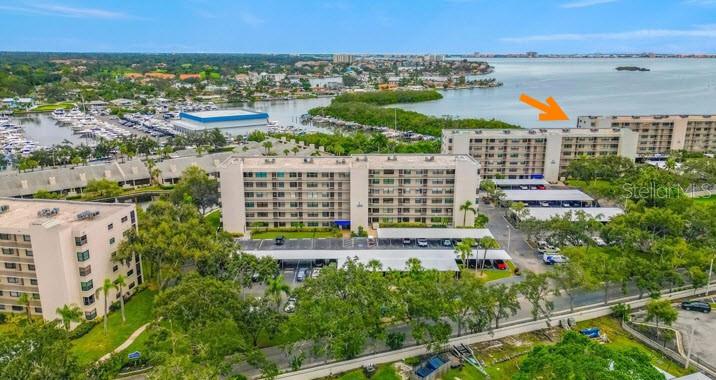 An aerial view shows a multi-story apartment complex near a marina and a body of water — 1332 PASADENA AVENUE S UNIT 501, SOUTH PASADENA, FL