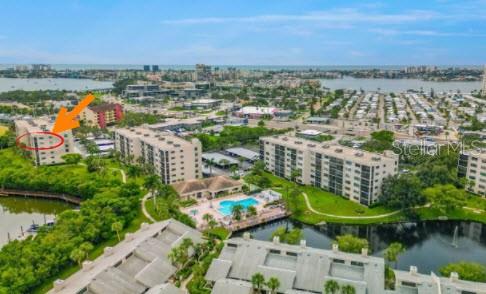 An aerial view shows a multi-story apartment complex with a pool and surrounding water — 1332 PASADENA AVENUE S UNIT 501, SOUTH PASADENA, FL