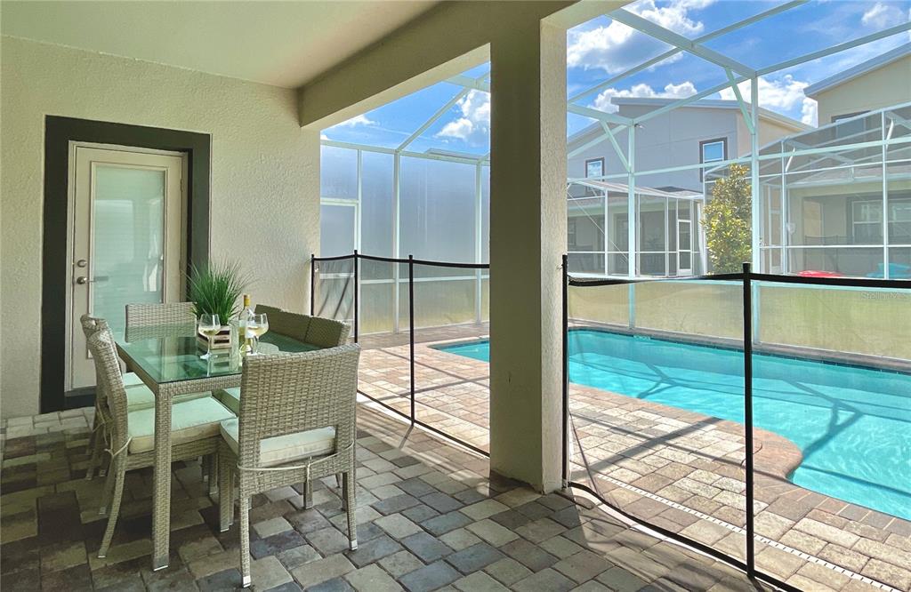 A covered patio features a dining set and a pool enclosed by a screen cage — 830 DROP SHOT DRIVE, DAVENPORT, FL