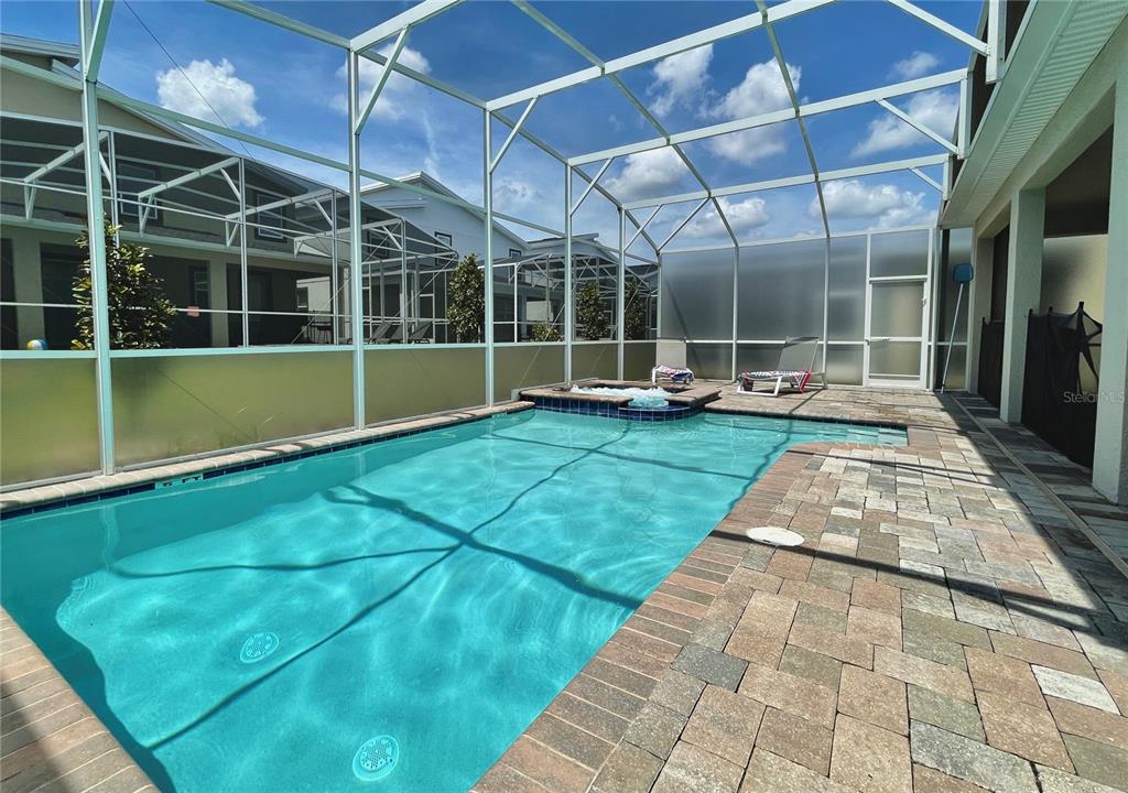 A swimming pool and hot tub are enclosed within a screened-in patio area — 830 DROP SHOT DRIVE, DAVENPORT, FL