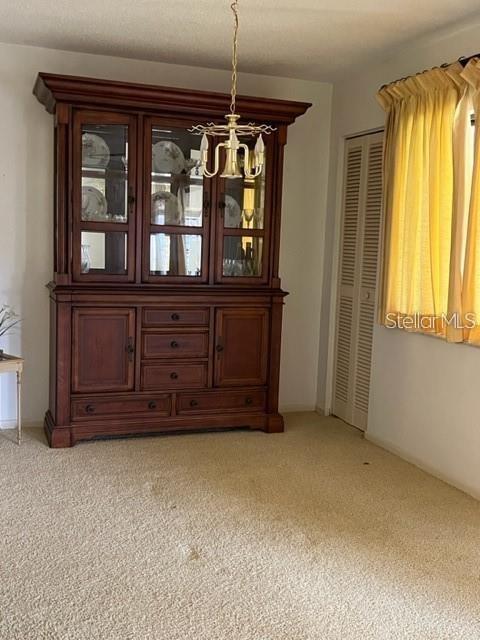 A dining room features a large wooden hutch, a hanging chandelier, and beige carpeting — 627 MIDWAY DRIVE UNIT B, OCALA, FL