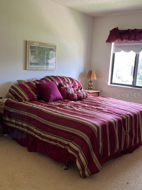 A bedroom features a bed with a striped burgundy comforter, a framed picture, and a window — 627 MIDWAY DRIVE UNIT B, OCALA, FL