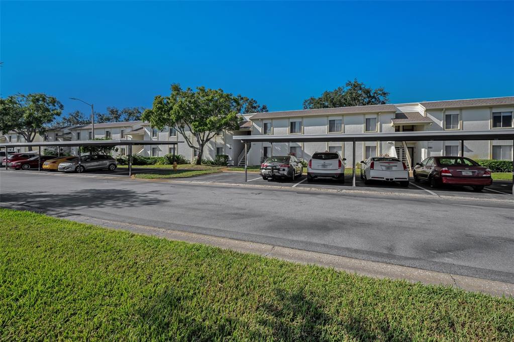 A two-story apartment building with covered parking spaces and several parked cars in front — 110 CYPRESS CT UNIT 3-82, OLDSMAR, FL