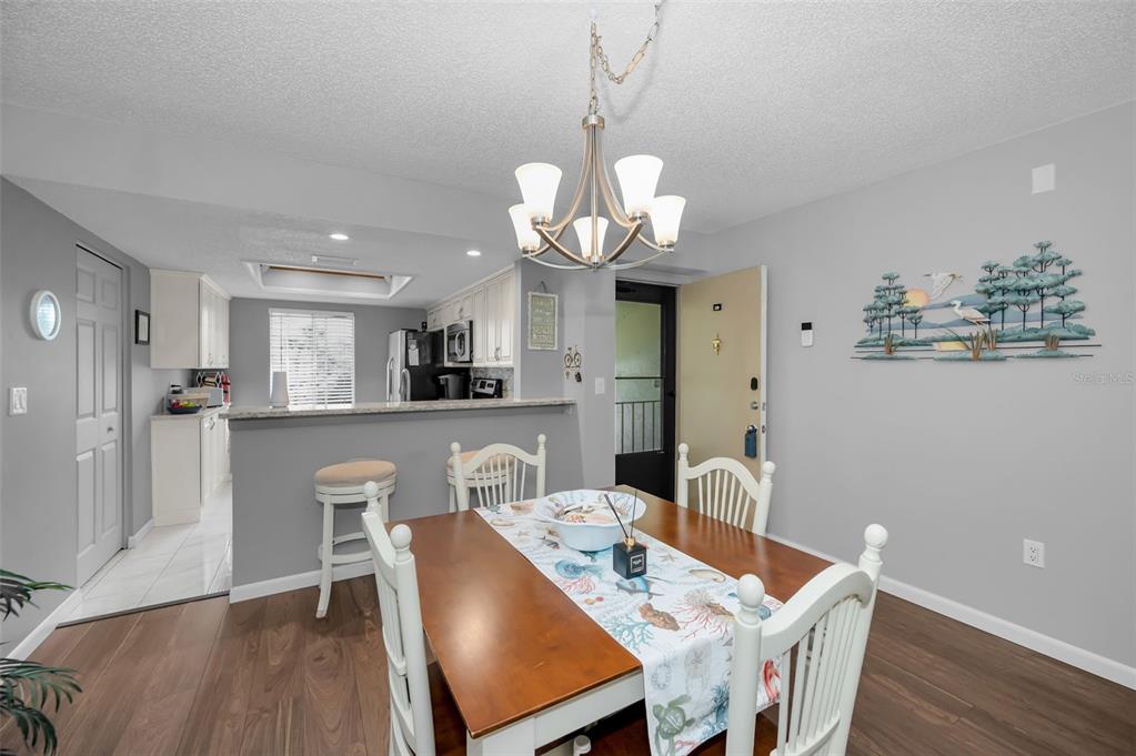 A dining area with a wooden table and chairs sits adjacent to a kitchen counter — 110 CYPRESS CT UNIT 3-82, OLDSMAR, FL
