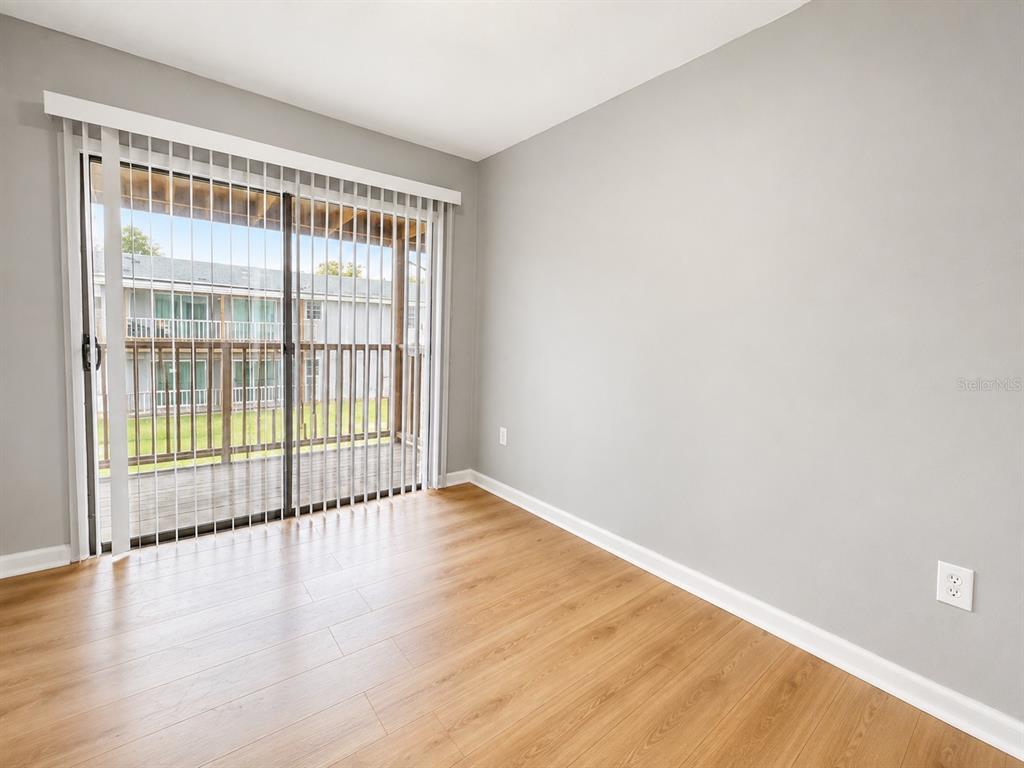An empty room with light wood-look flooring, gray walls, and a sliding glass door — 2763 L B MCLEOD ROAD UNIT C, ORLANDO, FL