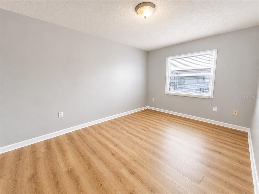 An empty bedroom features light gray walls, wood-look flooring, a window with blinds, and a ceiling light — 2763 L B MCLEOD ROAD UNIT C, ORLANDO, FL