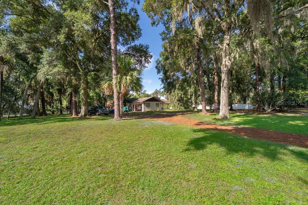 A detached garage sits at the end of a dirt driveway surrounded by mature trees — 1715 W LAKE MARY BOULEVARD, LAKE MARY, FL
