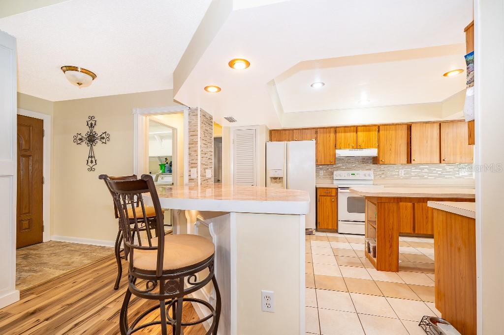 A kitchen with wood cabinets, tile flooring, and a breakfast bar with a stool — 1715 W LAKE MARY BOULEVARD, LAKE MARY, FL