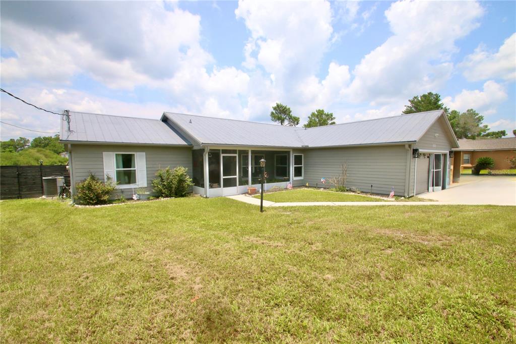 A gray single-story house with a metal roof, attached garage, and a screened front porch — 1812 WHIPPLE DRIVE, DELTONA, FL