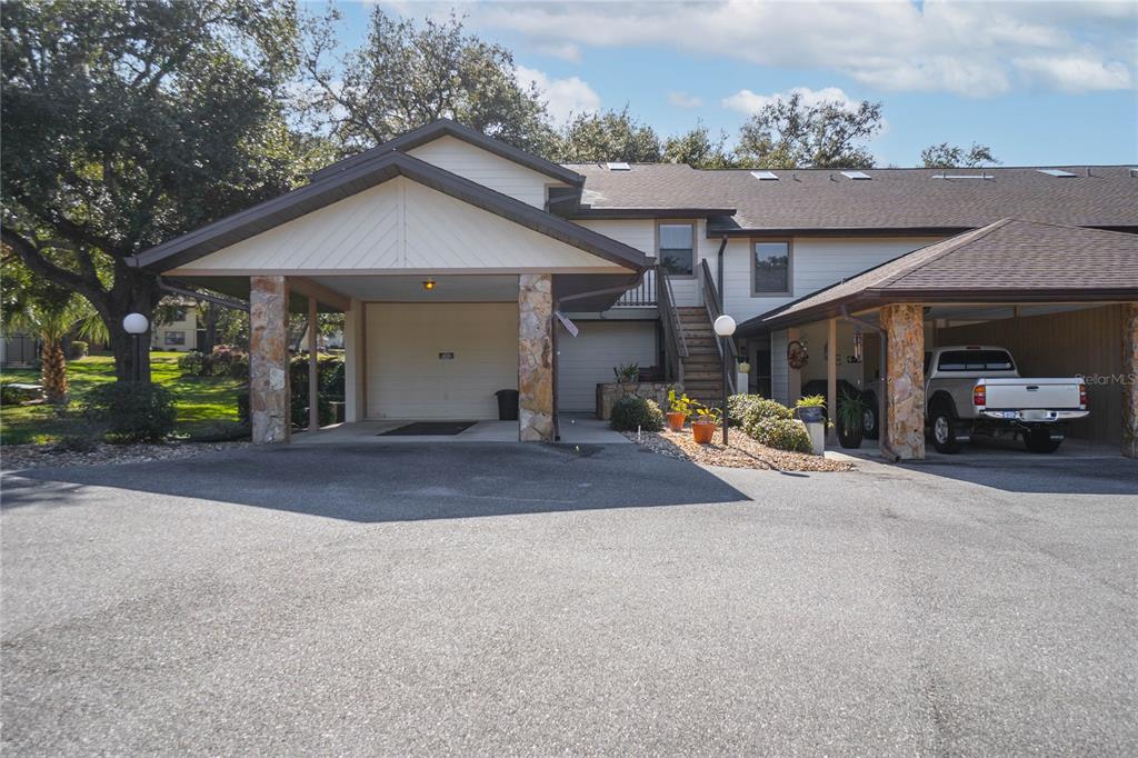 An exterior view of a multi-unit residential building featuring two covered carports and stairs — 240 E GLASSBORO COURT UNIT 4A, HERNANDO, FL