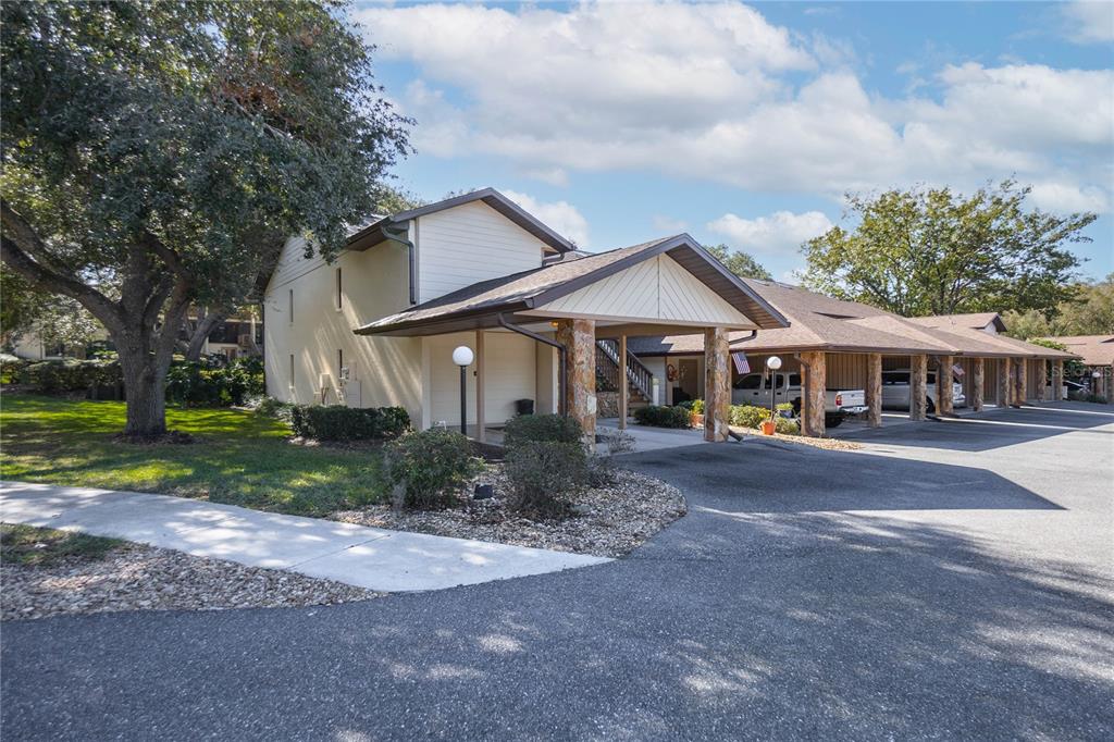 A multi-unit residential building with covered parking carports and stone-accented support pillars — 240 E GLASSBORO COURT UNIT 4A, HERNANDO, FL