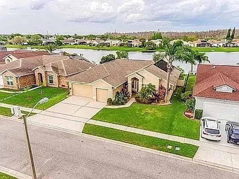 An aerial view shows suburban houses with driveways and lawns bordering a lake — 2415 RAVEN CROFT COURT, ORLANDO, FL