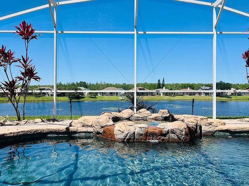 A swimming pool and rock-faced spa are enclosed by a screen overlooking a lake — 2415 RAVEN CROFT COURT, ORLANDO, FL