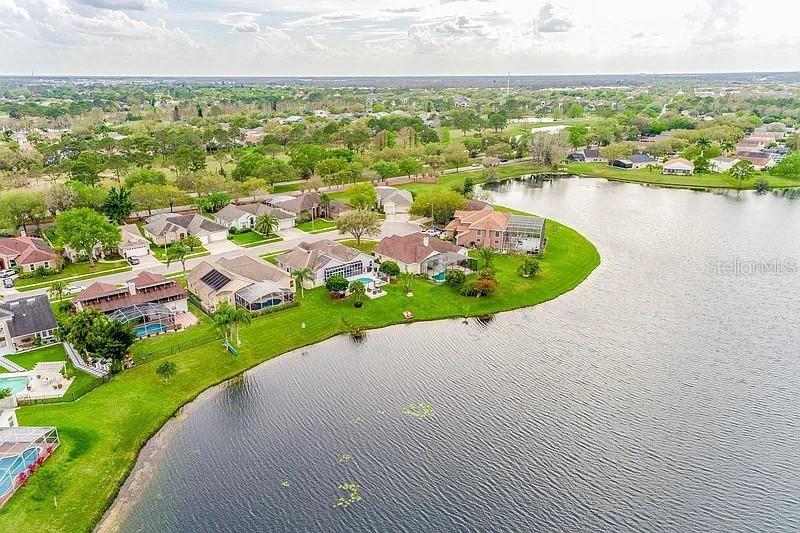 An aerial view shows a residential neighborhood with houses situated along a lakefront — 2415 RAVEN CROFT COURT, ORLANDO, FL