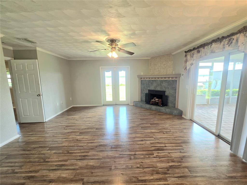 A living room features wood-look flooring, a corner fireplace, a ceiling fan, and sliding glass doors — 4414 BONNET LAKE DRIVE, HAINES CITY, FL