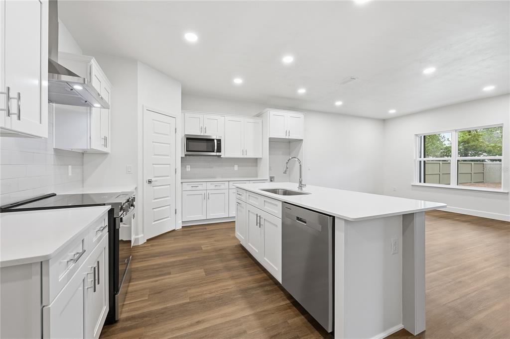 An empty bedroom features white walls, wood-look tile flooring, a tray ceiling, and a window — 1132 SW 67TH WAY, GAINESVILLE, FL